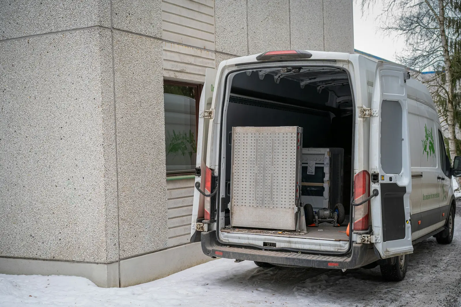 Weißer Transporter mit offenen Hecktüren, beladen mit einem Möbelstück
